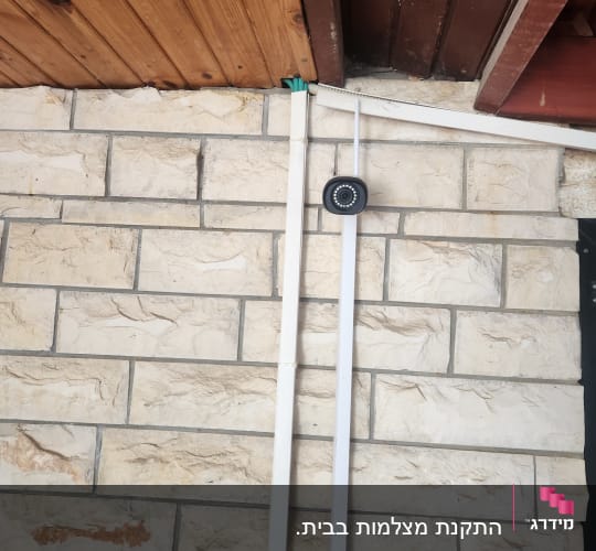 מצלמת אבטחה מותקנת על קיר אבן עם כבלים